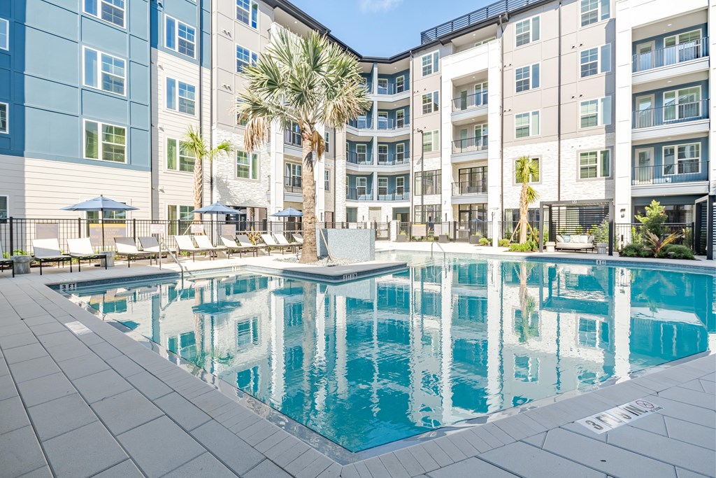 A swimming pool in front of a multi-story apartment building.