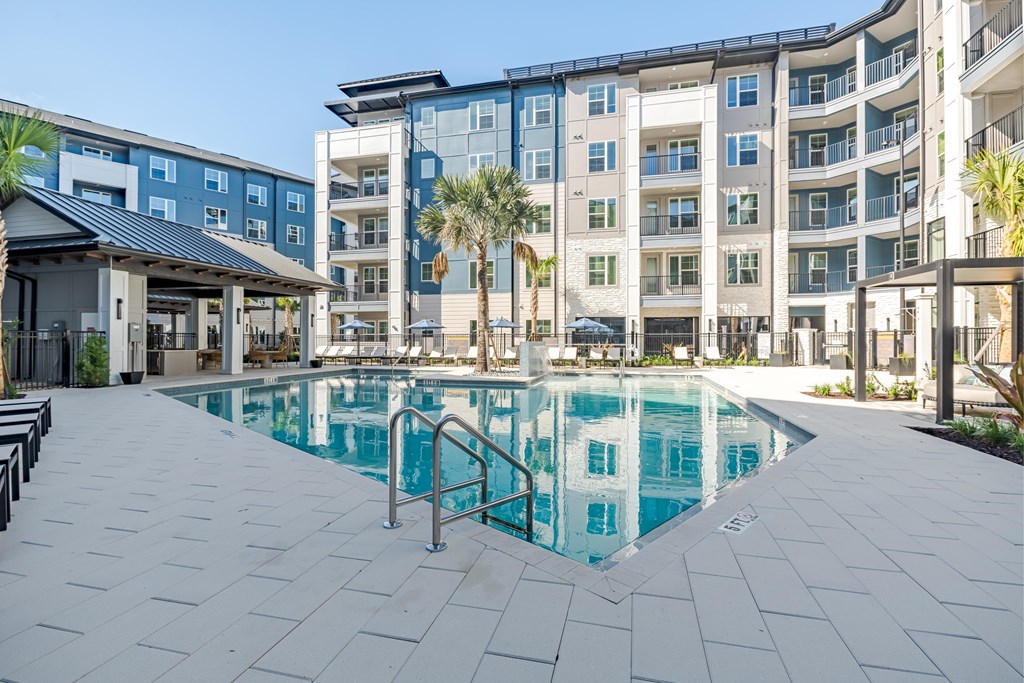 A large swimming pool in front of a multi-story apartment building.