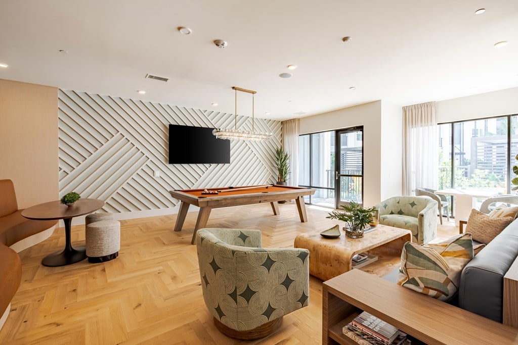 A living room with a wooden floor and a white wall with a black television.