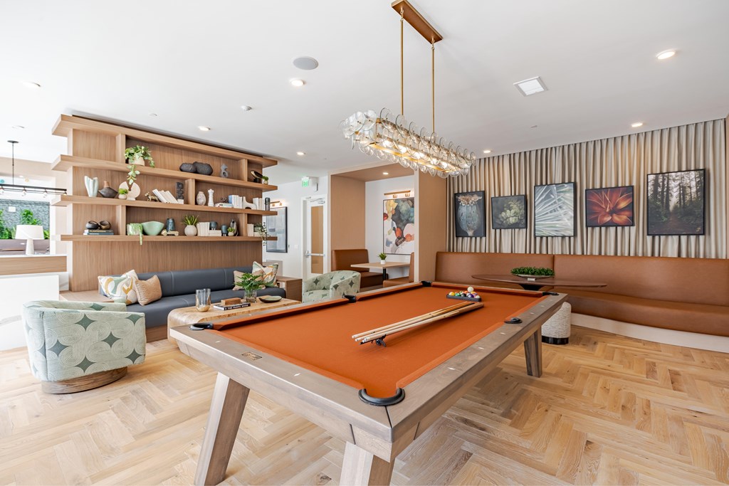 A pool table is in the middle of a room with a couch and a chair.