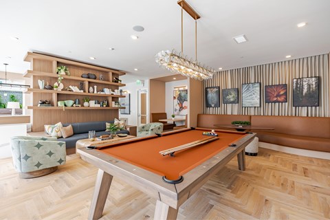 A pool table is in the middle of a room with a couch and a chair.