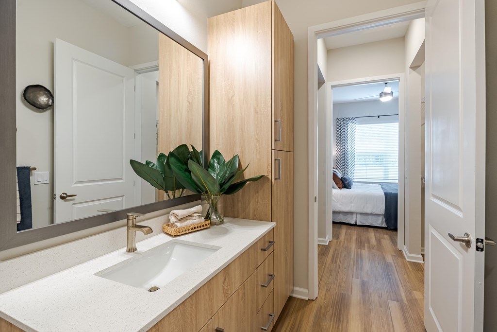 A bathroom with a sink, mirror, and wooden cabinets.