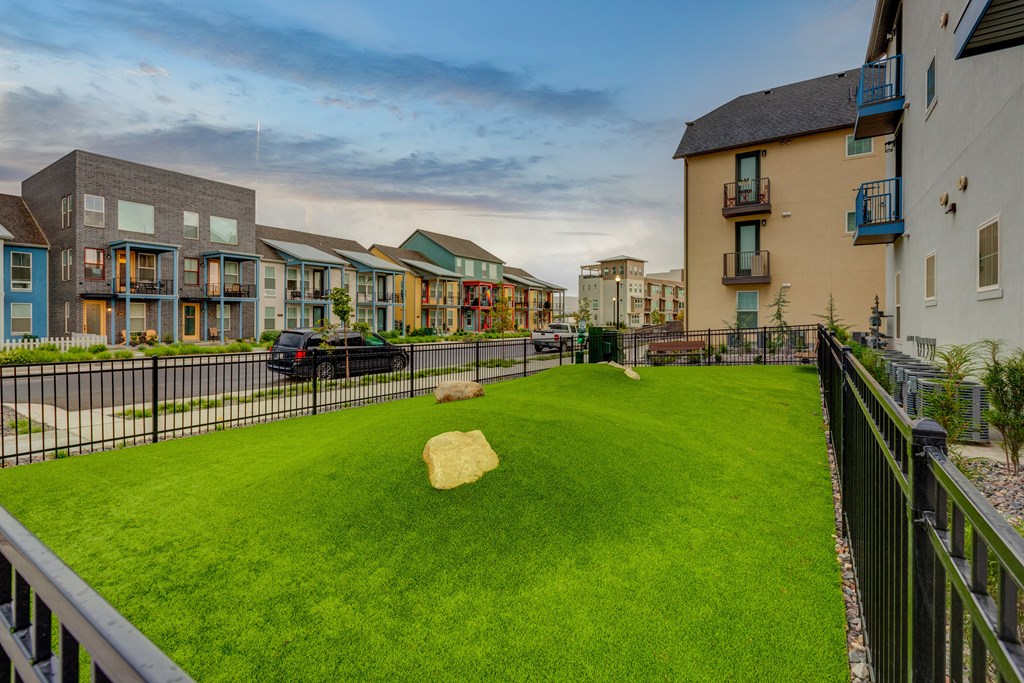 a yard with a rock on the grass in front of some houses