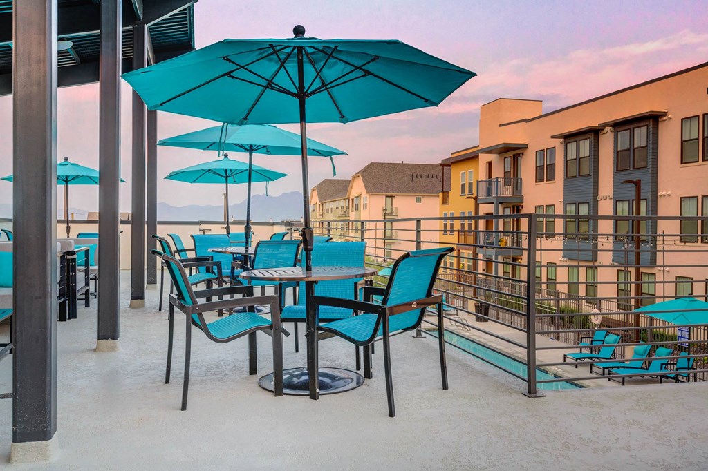 a patio with umbrellas and tables and chairs on a balcony