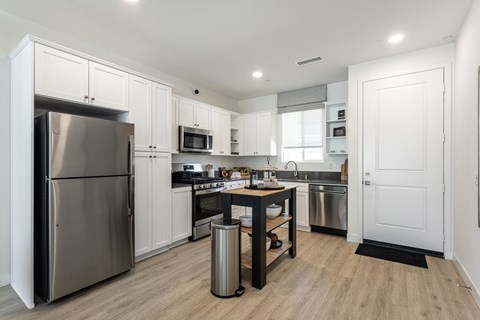 a large kitchen with stainless steel appliances and white cabinets