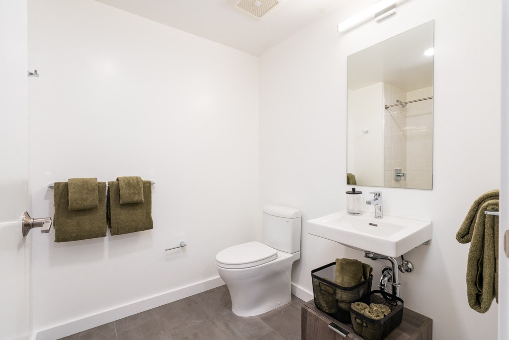 a bathroom with white walls and a white toilet next to a white sink and mirror