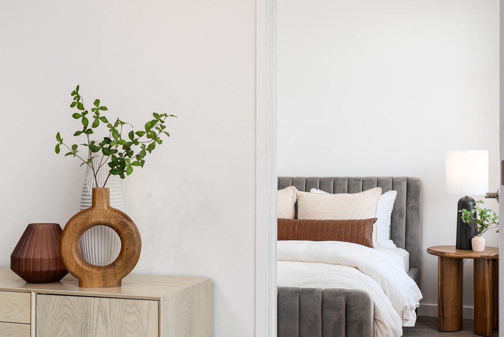 a bedroom with white walls and a wooden vase with a plant in it