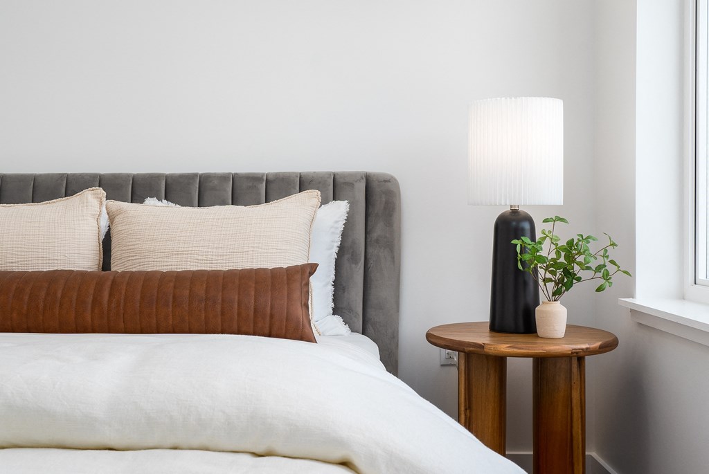 a bedroom with a bed and a table with a lamp on it