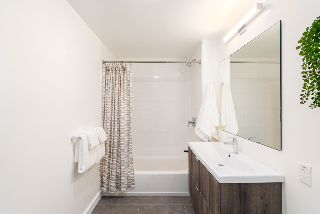 a bathroom with a white sink and bathtub with a shower curtain