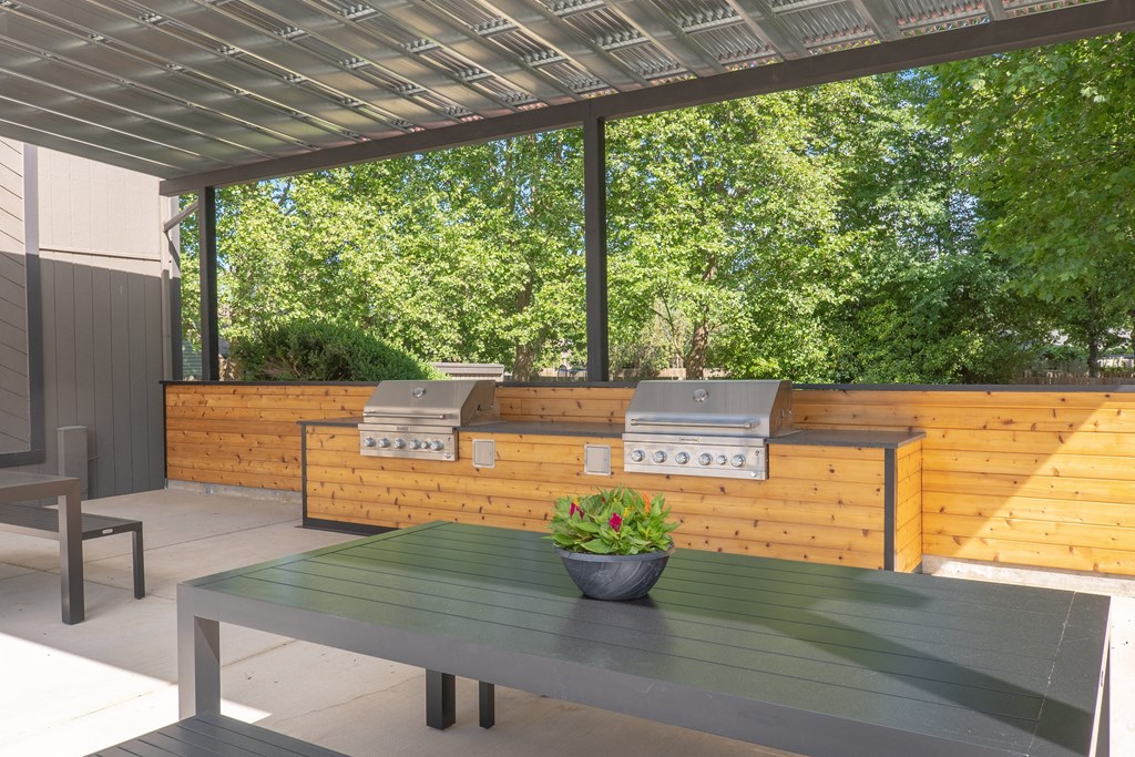 an outdoor kitchen with two bbq grills and a table with a potted plant at Veri at Timberhill, Oregon, 97330