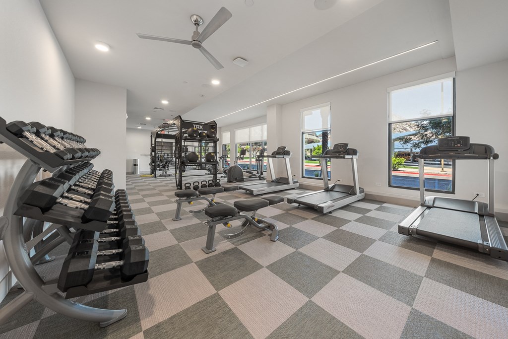 a gym with treadmills and other exercise equipment in a building with windows