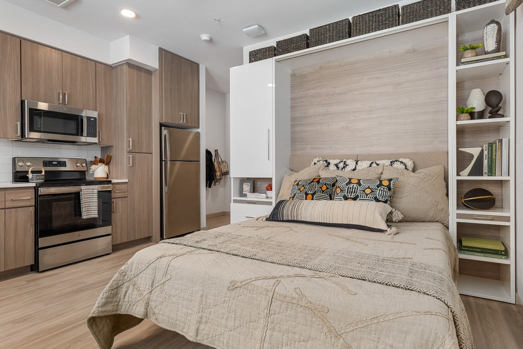 a bedroom with a bed and a kitchen