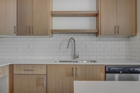 a kitchen with white tile and wooden cabinets and a sink