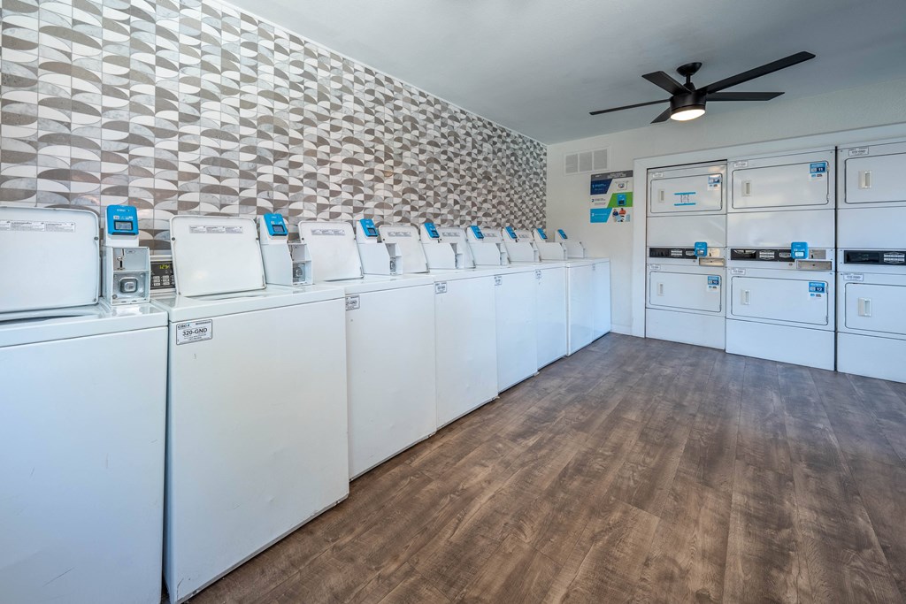 a laundry room with white washer and dryers and a ceiling fan