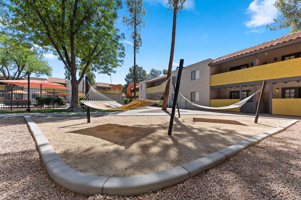 a playground with two hammocks and a building in the background