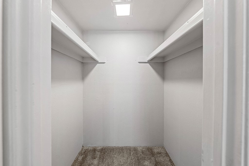 a walk in closet with white walls and white shelves