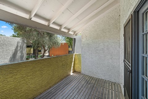 a balcony with a door and a tree in the background