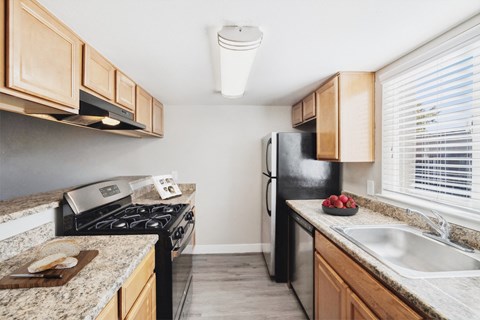 A kitchen with a black refrigerator and a stove top oven.