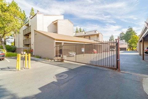 A gated entrance to a parking lot with a building in the background.