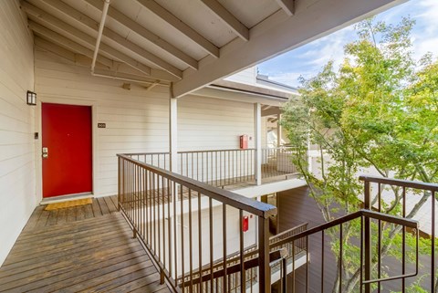 A red door is on the left side of a white building.