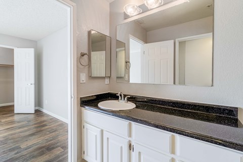 A bathroom with a sink, mirror, and wooden floors.