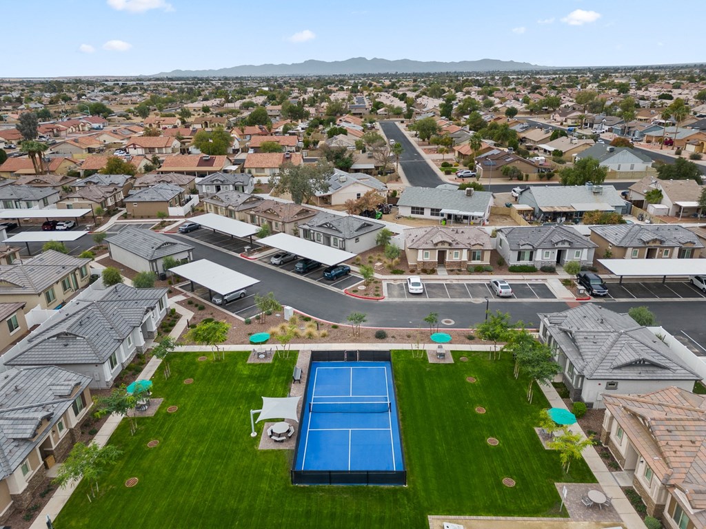 an aerial view of a tennis court and a pool large green area