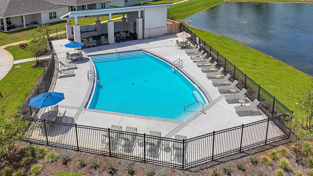 an aerial view of a swimming pool with chairs and umbrellas and a house