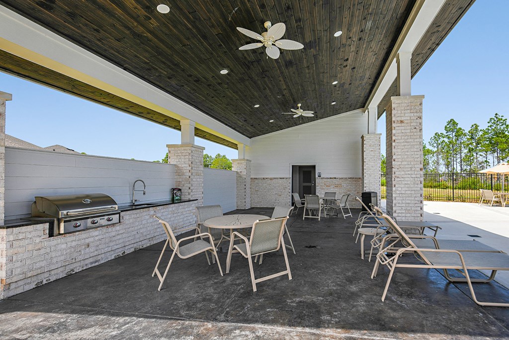 a patio with tables and chairs and a barbecue grill