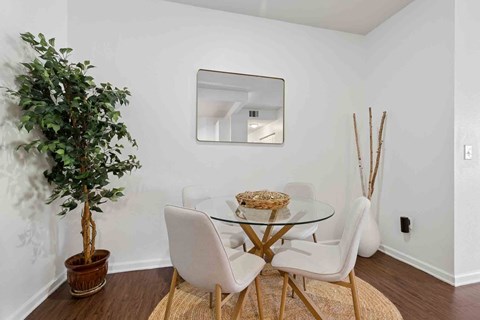 A dining room with a glass table and white chairs.