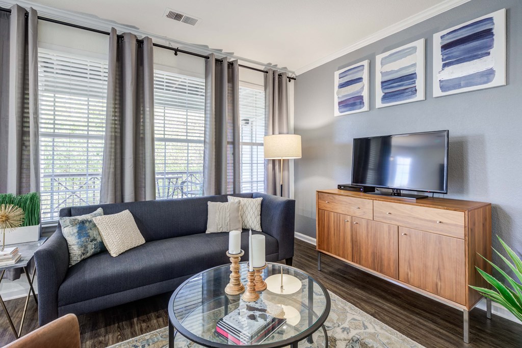 a living room with a couch and a glass coffee table and a television