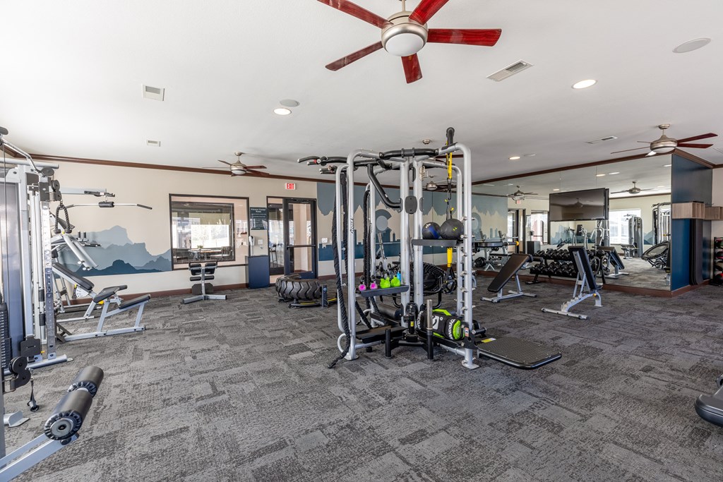 a gym with weights and cardio machines and a ceiling fan