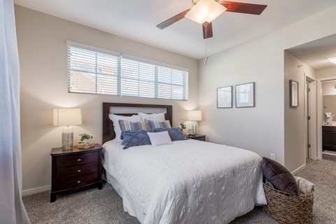 A bedroom with a bed, two nightstands with lamps, and a ceiling fan.