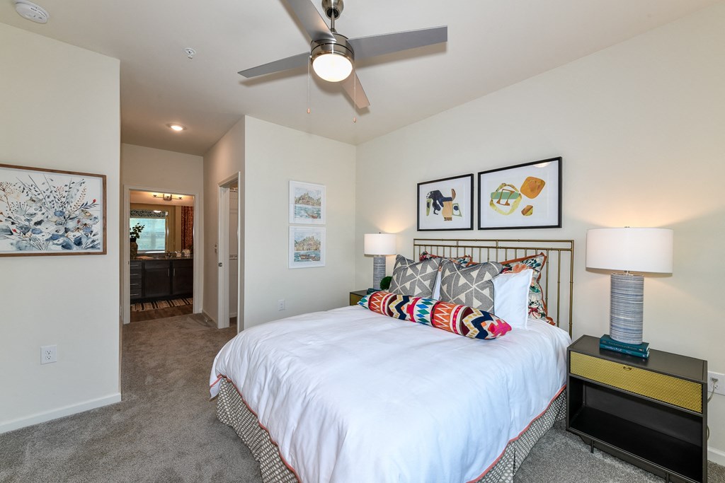a bedroom with a large white bed and a ceiling fan