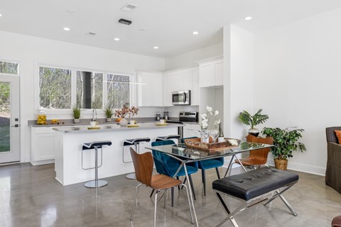 A modern kitchen with white cabinets and a dining table set with chairs.