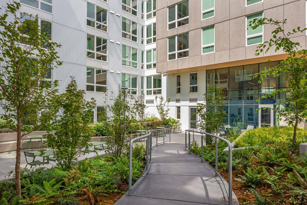 a walkway in front of an office building with trees and plants