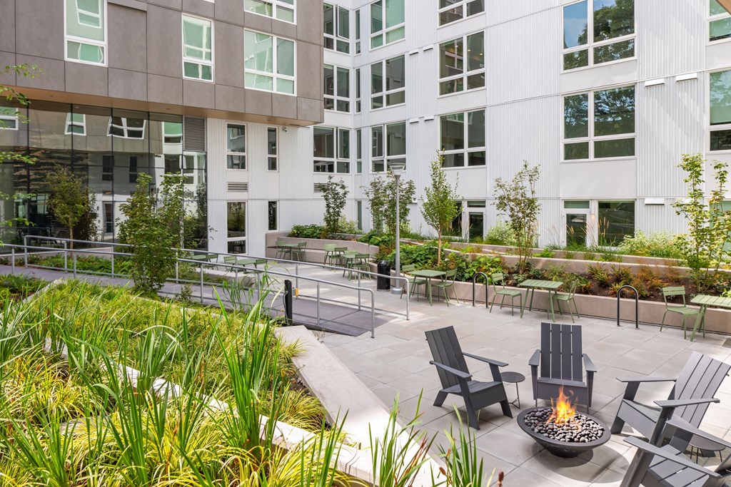 an outdoor patio with chairs and a fire pit in front of an office building