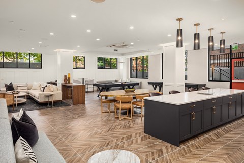 a clubhouse with couches tables and chairs and a kitchen