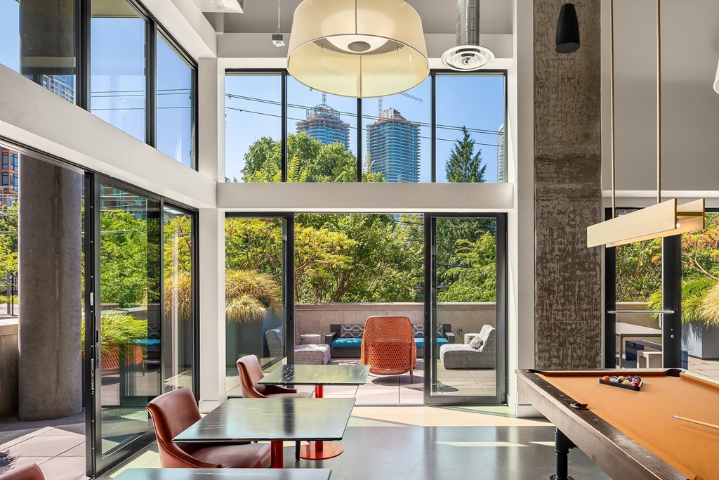 a living room with a table and chairs and large windows