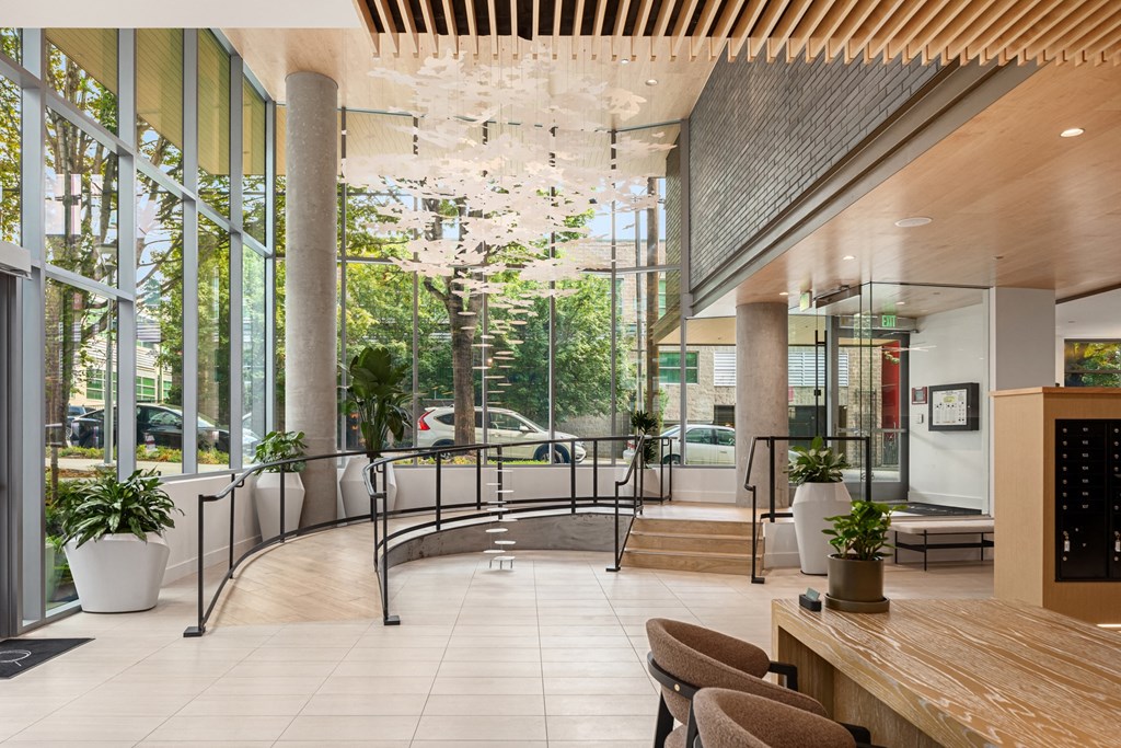 the lobby of a building with large windows and a table and chairs