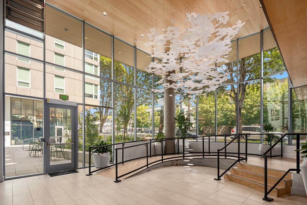 the lobby of a building  with large glass windows and a large tree in therium