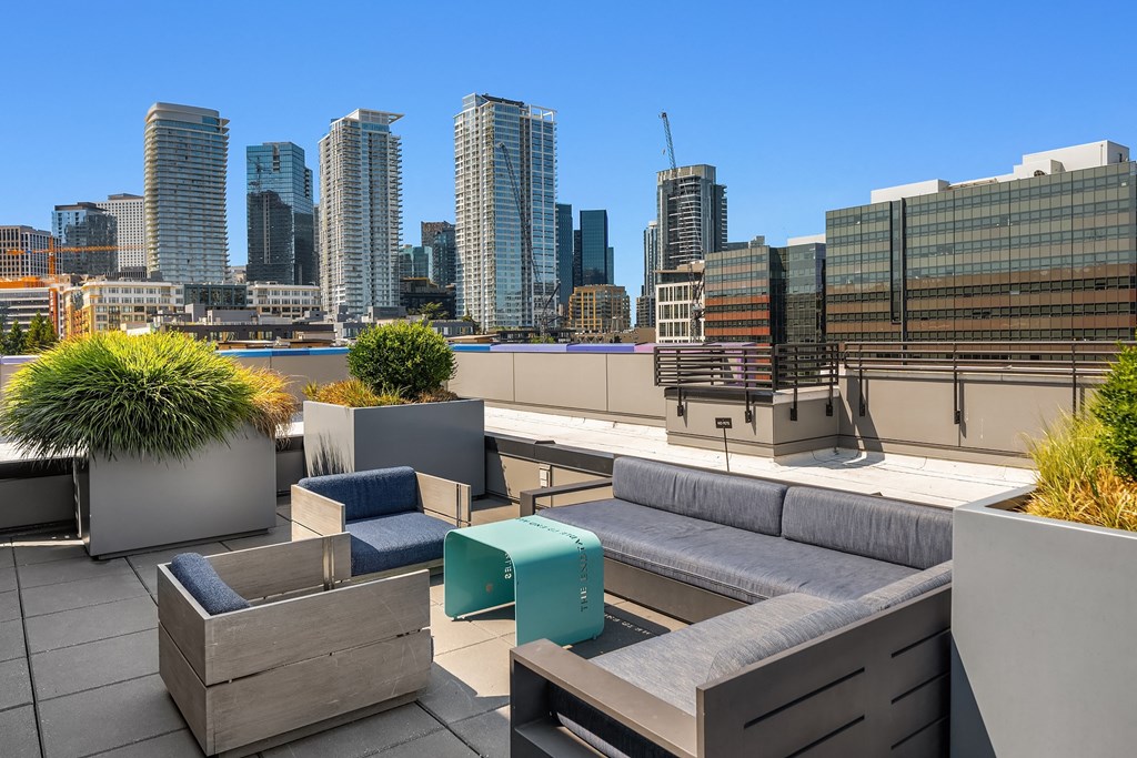 a roof terrace with couches and tables and a view of the city