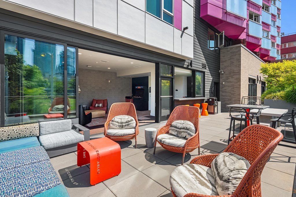 a patio with chairs and tables and a building in the background