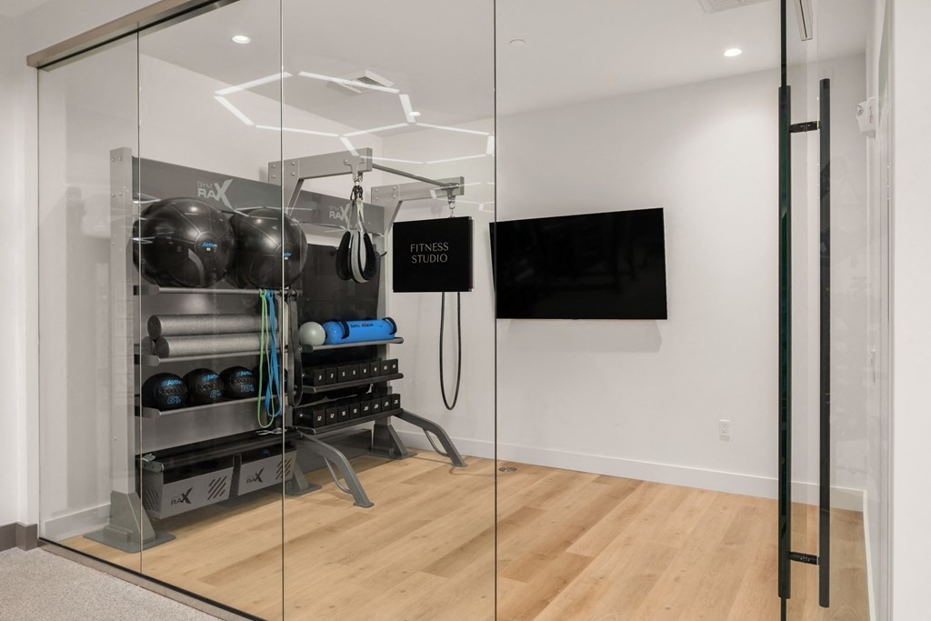a fitness room with glass walls and a tv on the wall