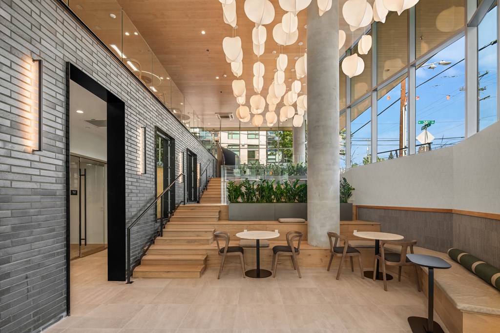 a large lobby with tables and chairs and a staircase