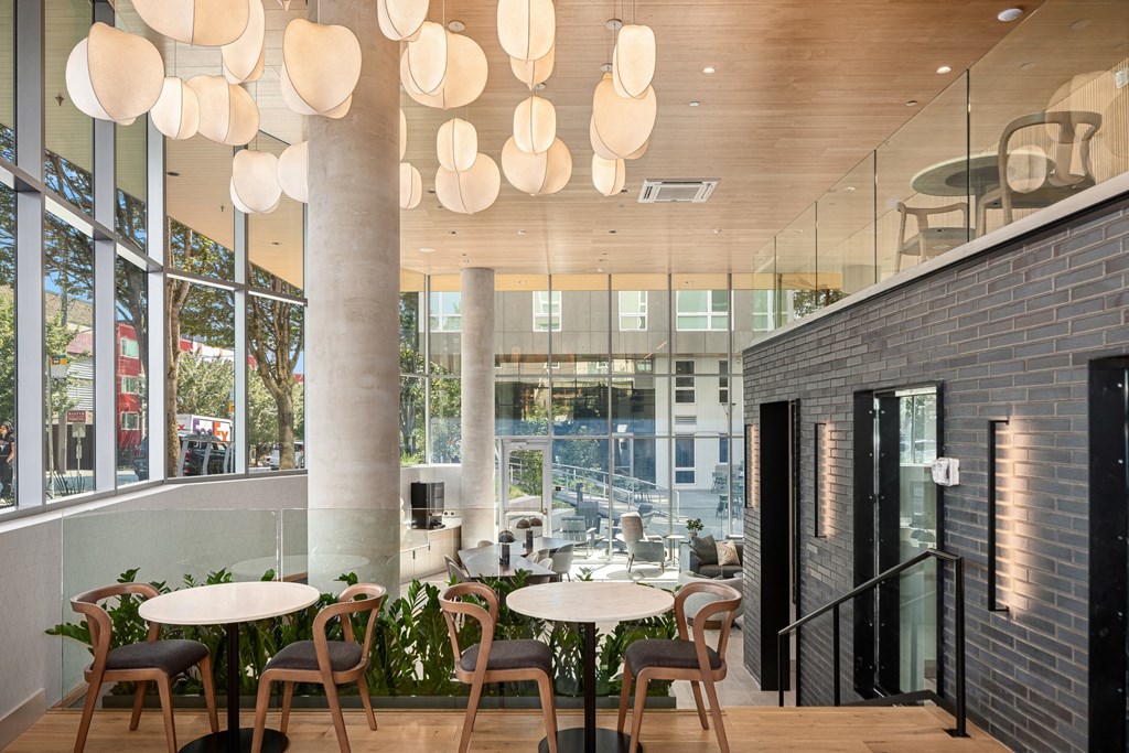 the  lobby of a building with tables and chairs and large windows