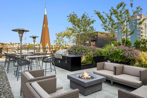 a rooftop patio with couches and tables and a fire pit