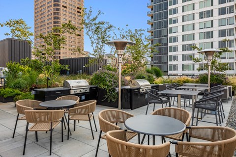 an outdoor patio with tables and chairs and barbecue grills