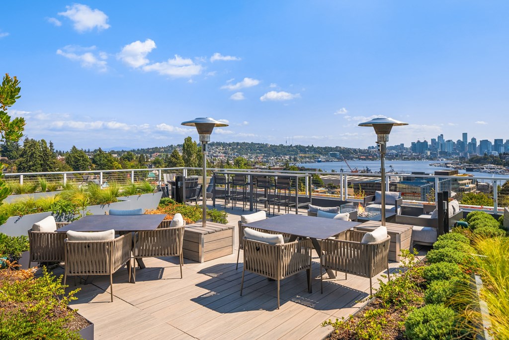 a rooftop patio with tables and chairs and a view of the city
