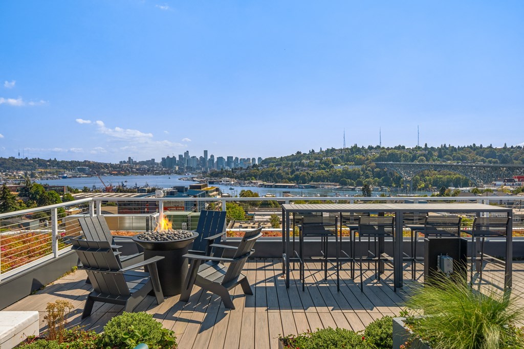 a deck with chairs and a fire pit and a view of the city