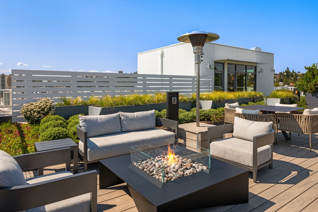 a roof deck with couches and chairs and a fire pit